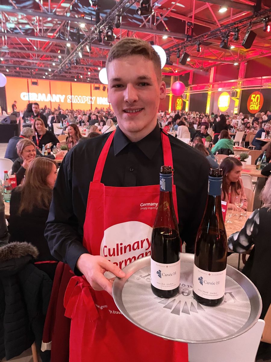 <who>Photo credit: Steve MacNaull/NowMedia Group</who>Simon served the Cuvee H red and white blend wines at the opening ceremony of the Germany Travel Mart in Chemnitz.
